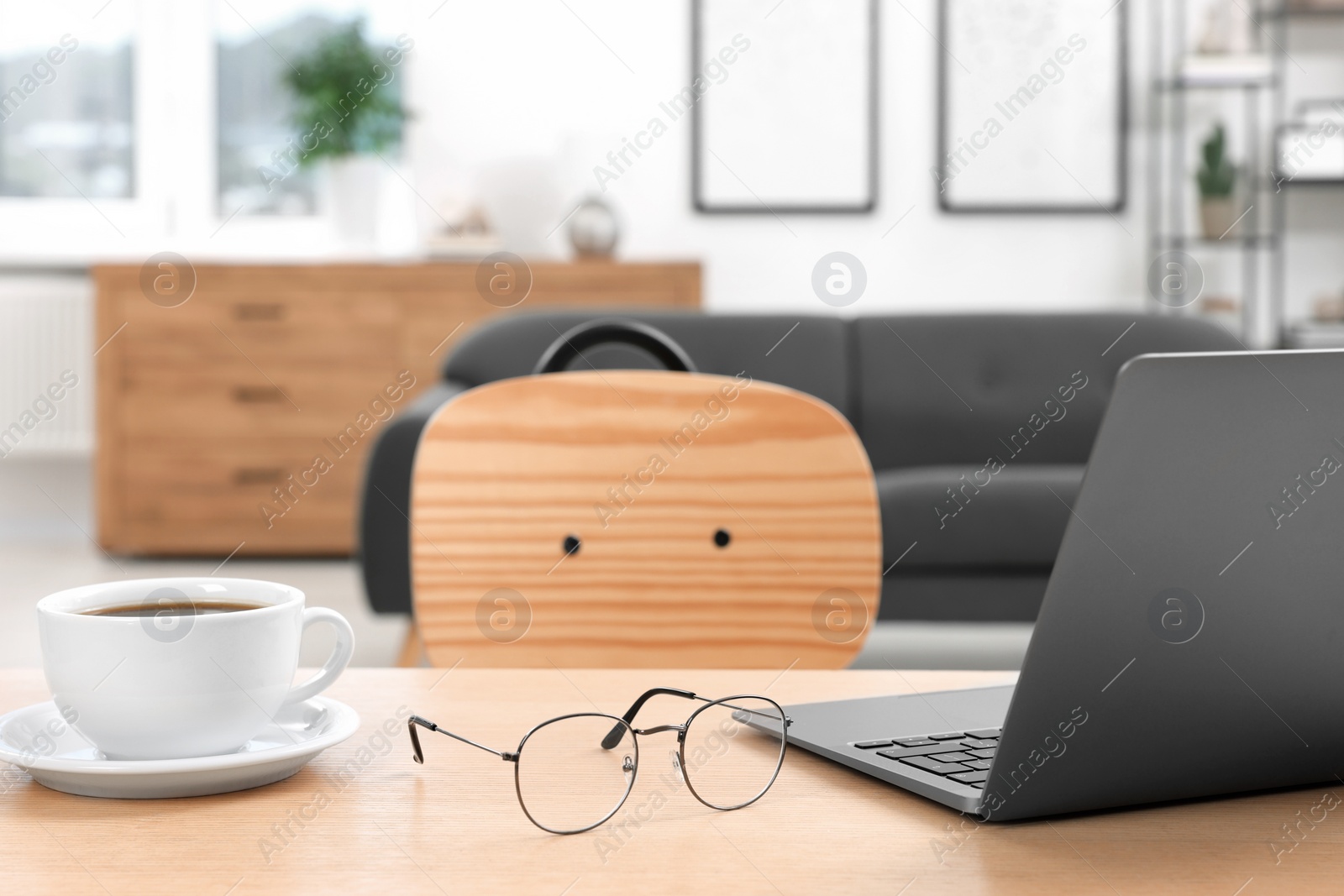 Photo of Home workspace. Laptop, glasses and cup of coffee on wooden desk in room