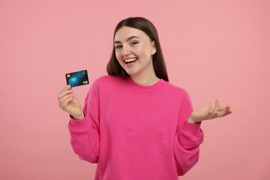 Happy woman with credit card on pink background