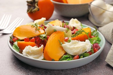 Photo of Delicious persimmon salad with cheese and pomegranate served on grey table