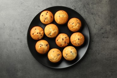 Photo of Delicious freshly baked muffins with chocolate chips on gray table, top view