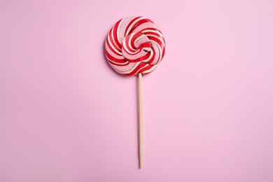 Stick with colorful lollipop swirl on pink background, top view