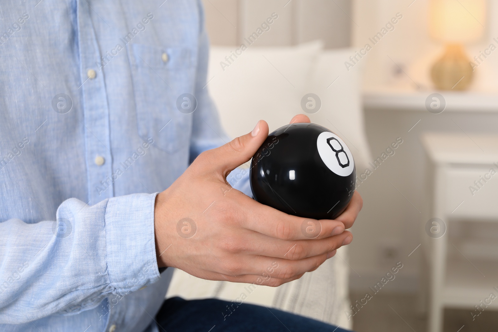 Photo of Man holding magic eight ball indoors, closeup