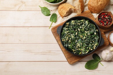 Photo of Tasty spinach dip with eggs in dish served on light wooden table, flat lay. Space for text