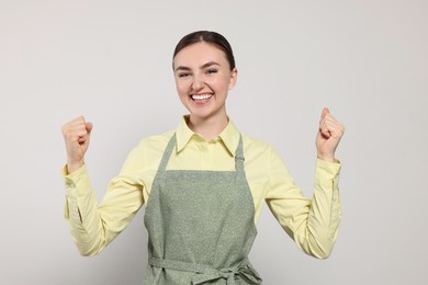 Photo of Beautiful young woman in clean apron with pattern on light grey background