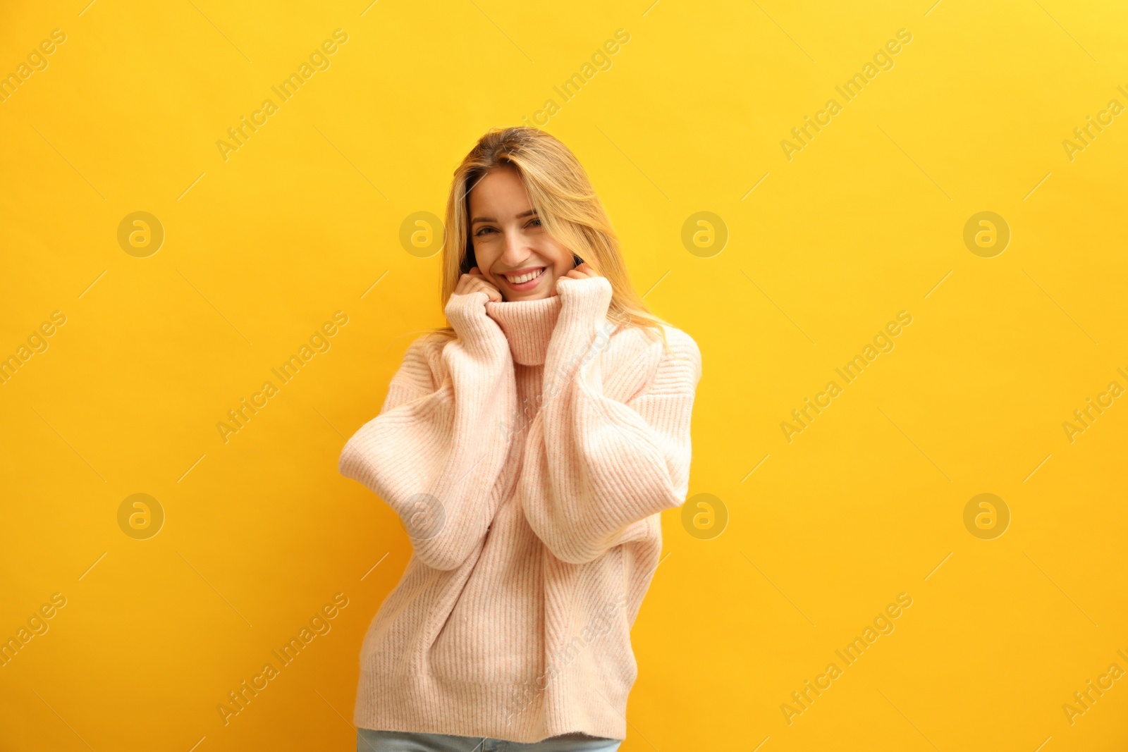 Photo of Beautiful young woman wearing knitted sweater on yellow background