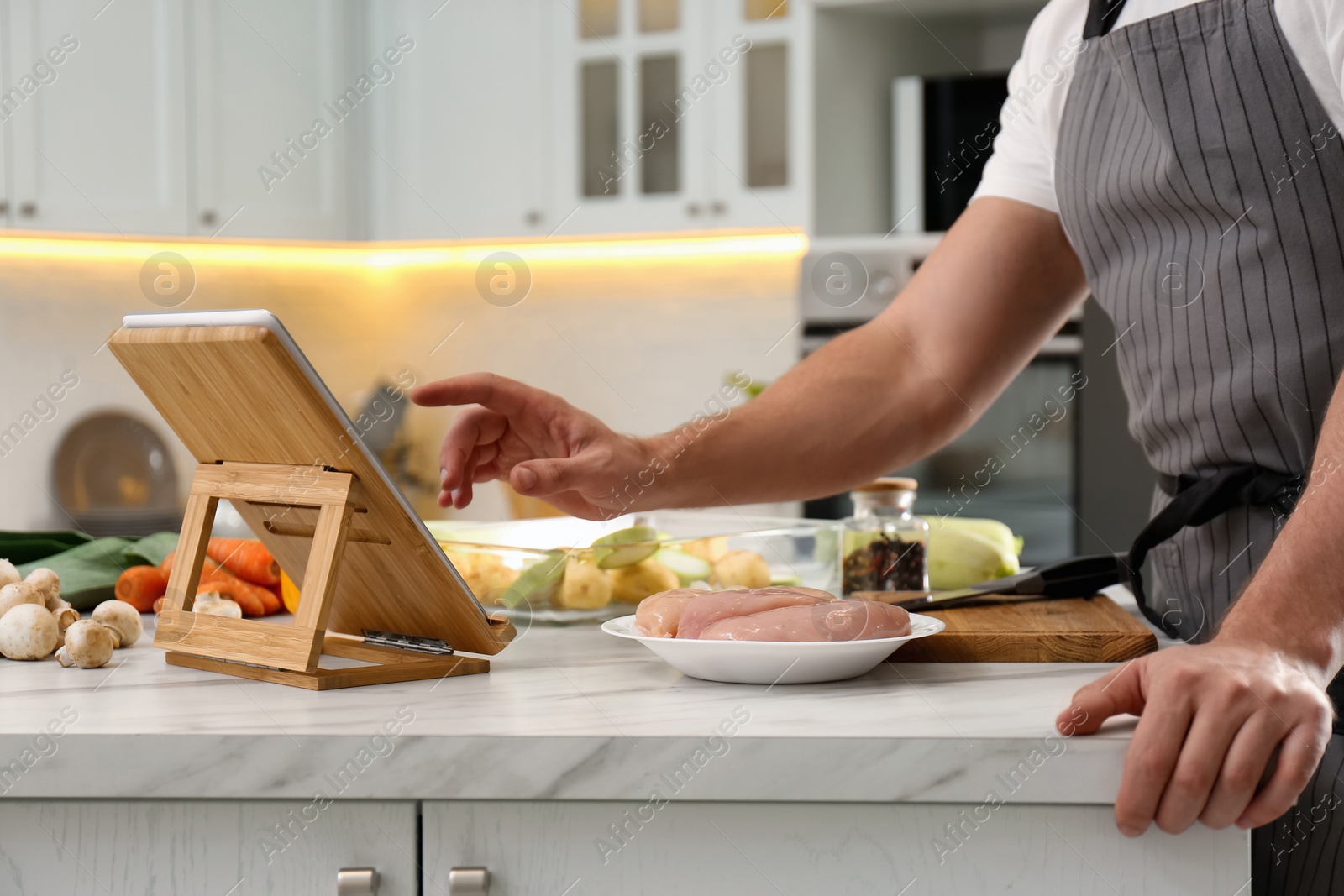 Photo of Man watching online cooking course via tablet in kitchen, closeup