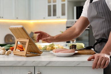 Photo of Man watching online cooking course via tablet in kitchen, closeup