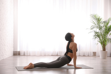 Photo of Young woman practicing cobra asana in yoga studio. Bhujangasana pose