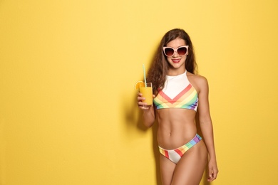 Beautiful young woman with inflatable ring and glass of cocktail on color background