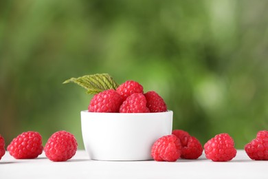 Photo of Tasty ripe raspberries and green leaf on white table outdoors