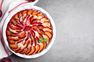 Photo of Delicious cake with plums on grey table, flat lay. Space for text