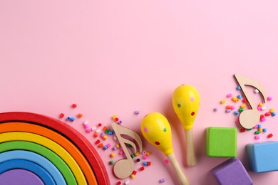 Baby song concept. Wooden notes, kids maracas and toys on pink background, flat lay. Space for text