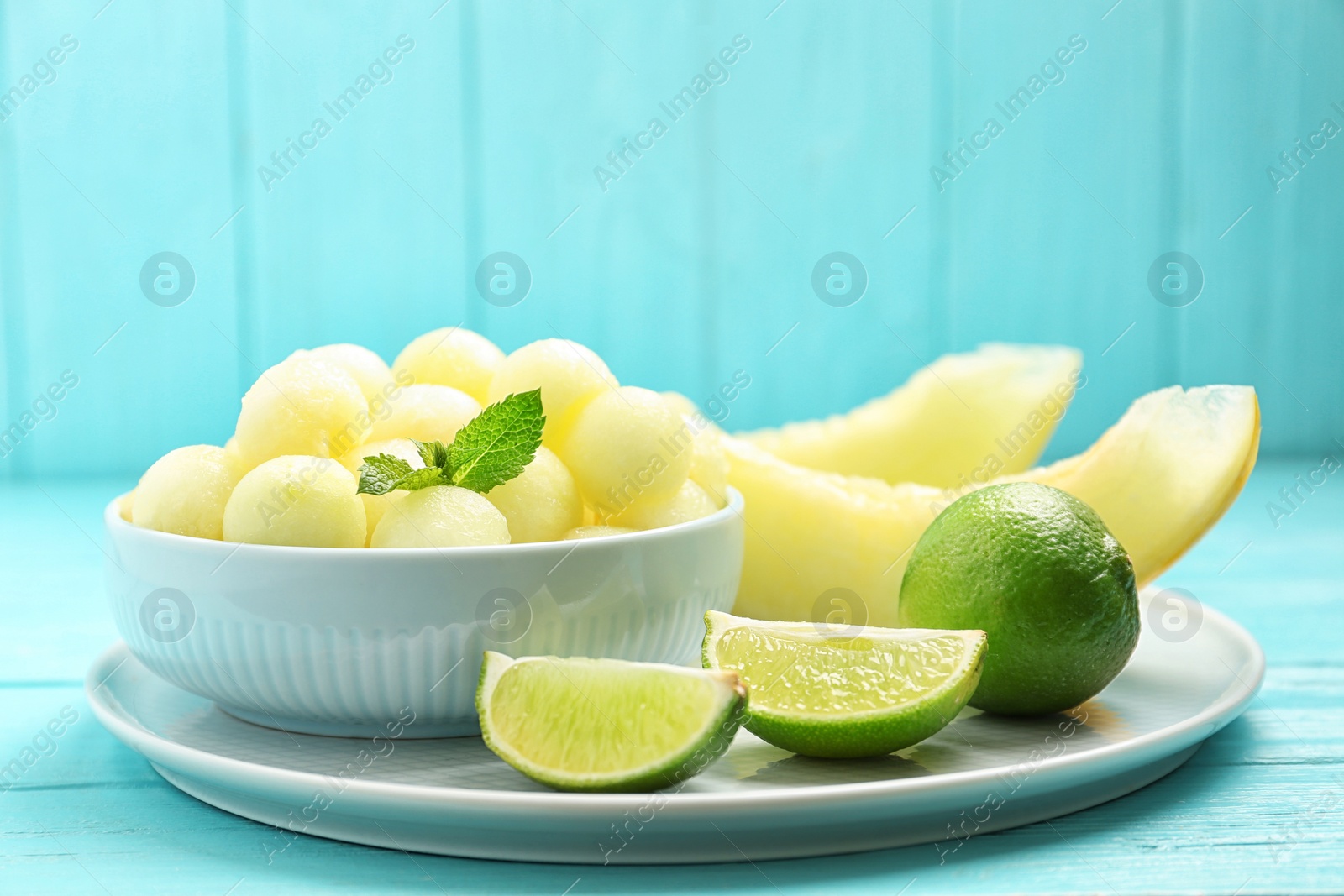 Photo of Melon balls with mint and lime on light blue wooden table