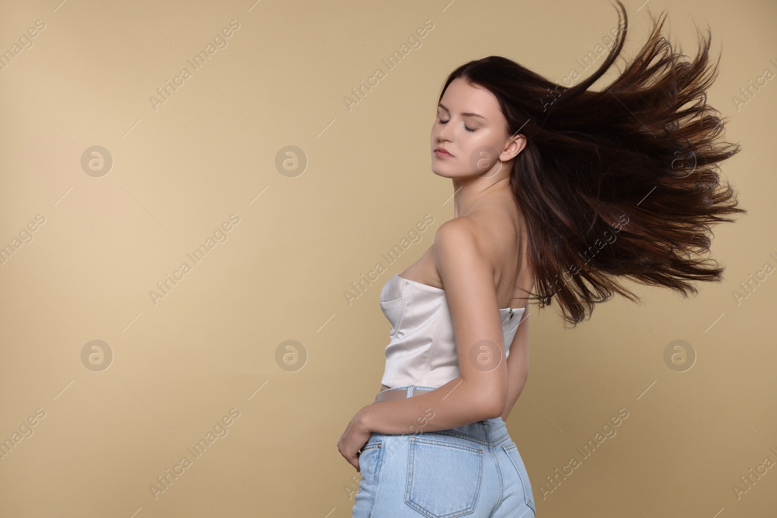 Photo of Portrait of beautiful young woman with healthy strong hair on beige background, space for text