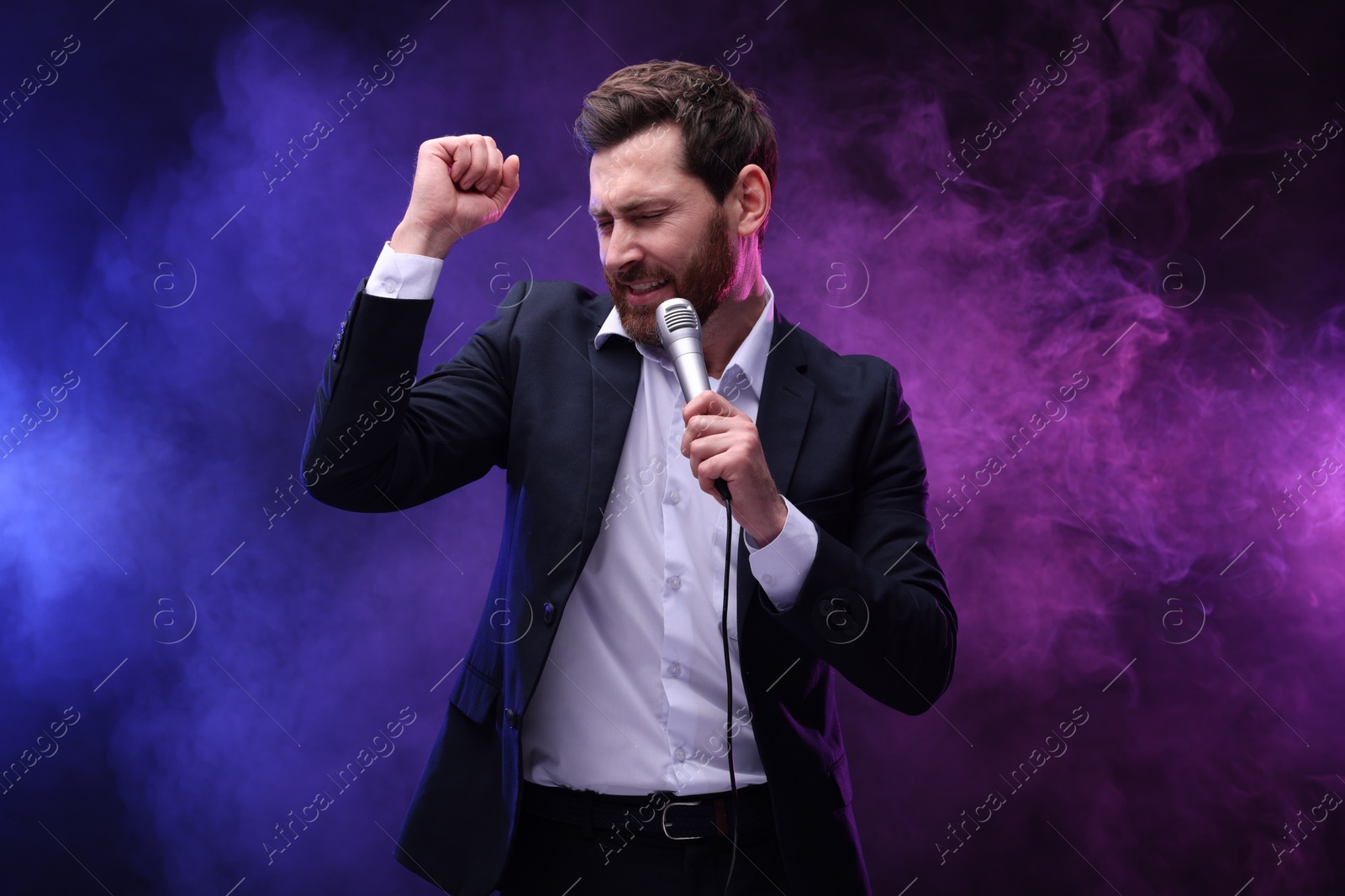 Photo of Emotional man with microphone singing in neon lights