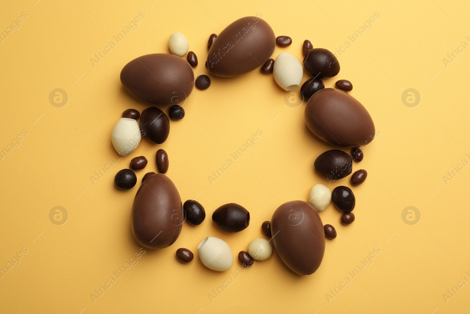 Photo of Flat lay composition with chocolate Easter eggs and space for text on color background