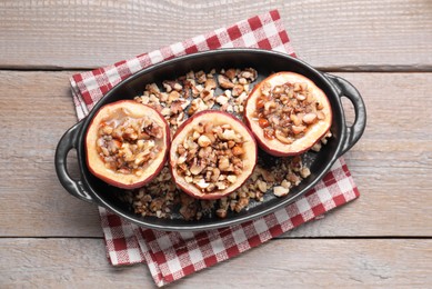 Tasty baked apples with nuts and honey in baking dish on wooden table, top view