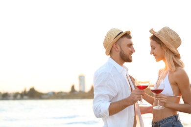 Photo of Young couple with glasses of wine on beach