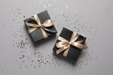 Photo of Beautiful gift boxes and confetti on grey background, flat lay