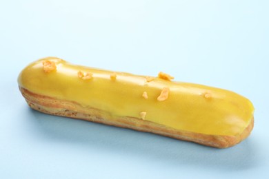 Photo of Delicious eclair covered with glaze on light blue background