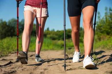 Photo of Women practicing Nordic walking with poles outdoors on sunny day, closeup