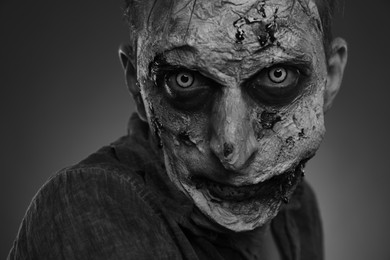 Closeup view of scary zombie on dark background, black and white effect. Halloween monster