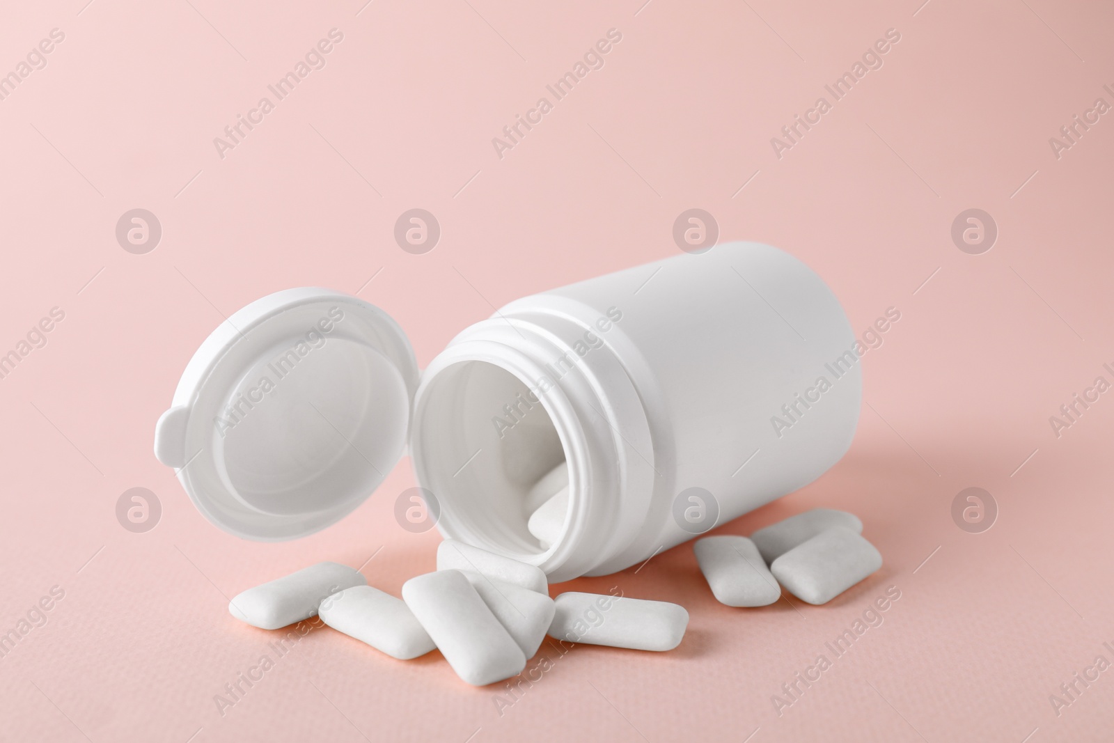 Photo of Jar with chewing gums on light pink background