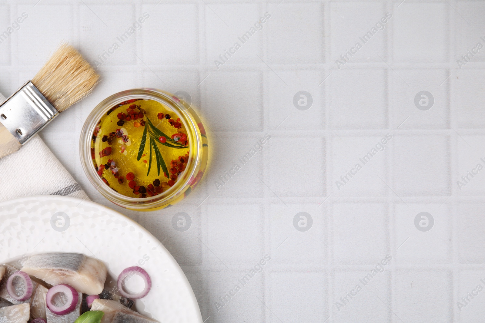 Photo of Tasty fish marinade in jar and herring on light tiled table, flat lay. Space for text