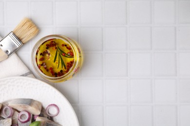 Tasty fish marinade in jar and herring on light tiled table, flat lay. Space for text