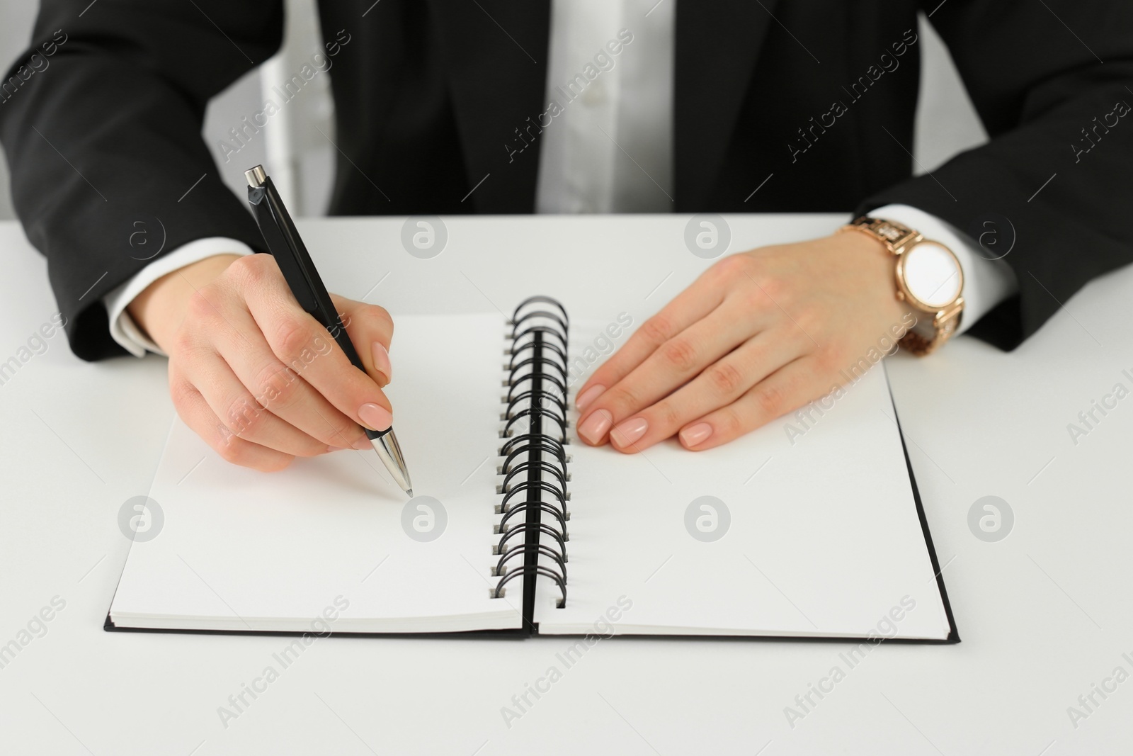 Photo of Woman writing in notebook at white table, closeup