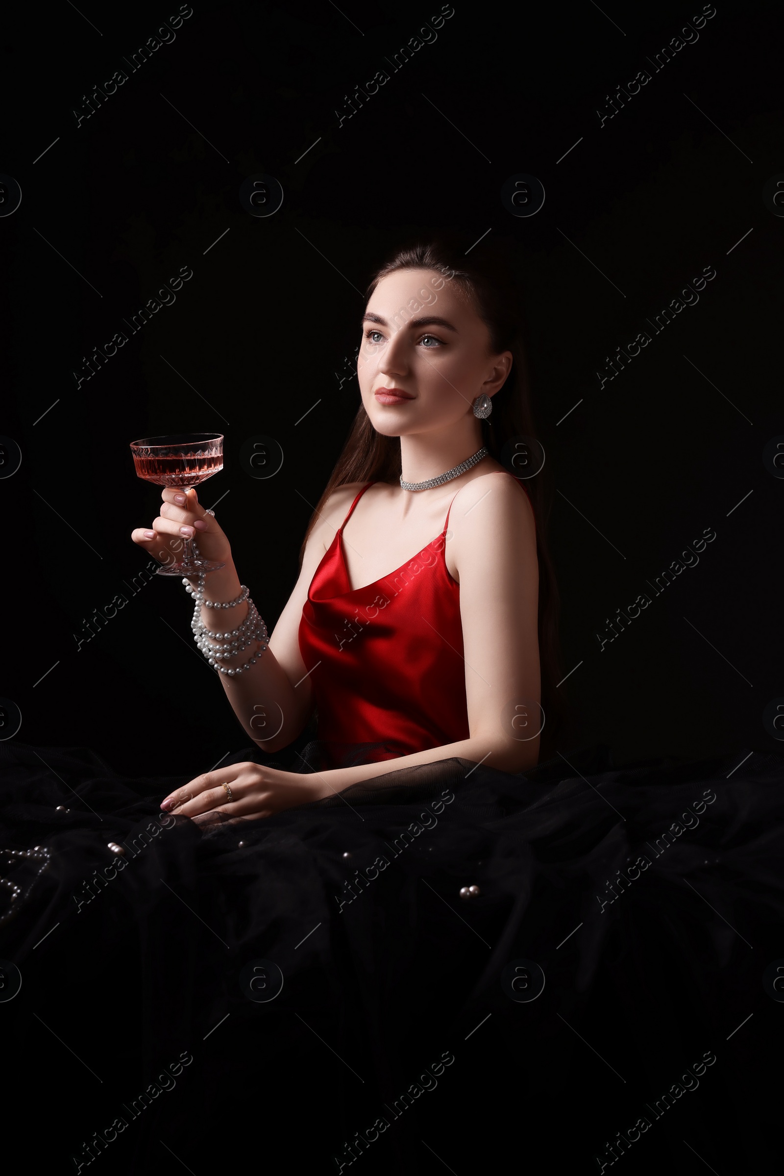 Photo of Fashionable photo of attractive young woman with glass of wine on black background