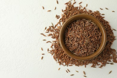 Caraway (Persian cumin) seeds and bowl on white table, top view. Space for text