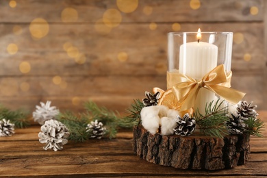Glass holder with burning candle and Christmas decor on wooden table. Space for text