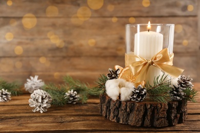 Photo of Glass holder with burning candle and Christmas decor on wooden table. Space for text