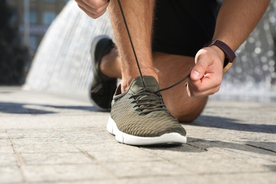 Photo of Sporty man tying shoelaces before running outdoors