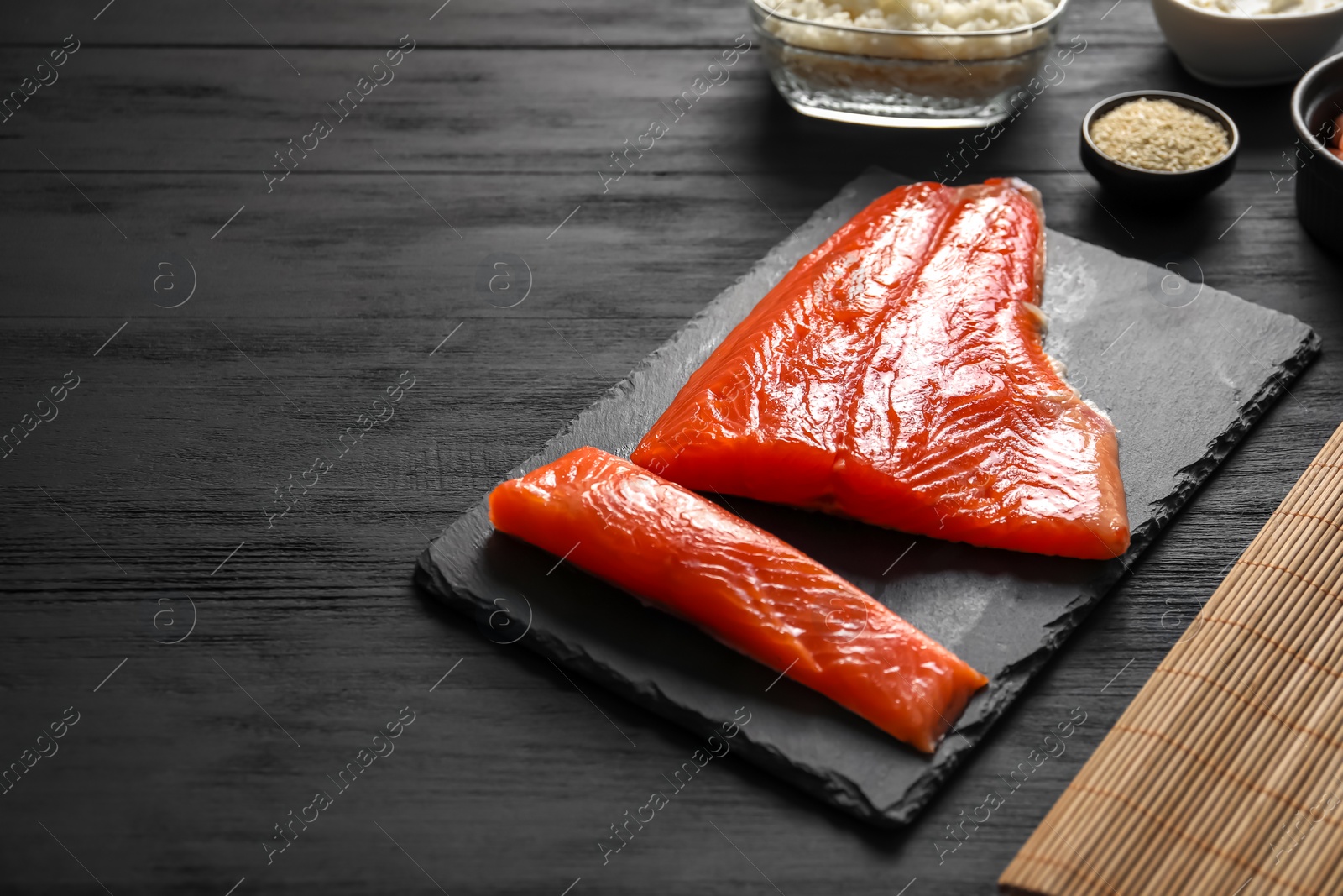 Photo of Fresh salmon for sushi on black wooden table. Space for text