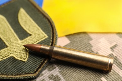 Photo of Bullet, Ukrainian flag and military patch on pixel camouflage, closeup