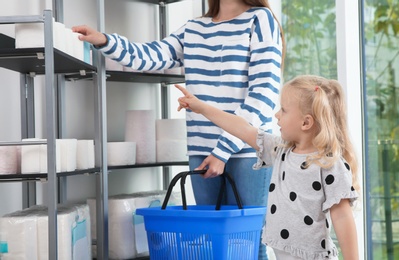 Young mother and little girl choosing toilet paper in shop