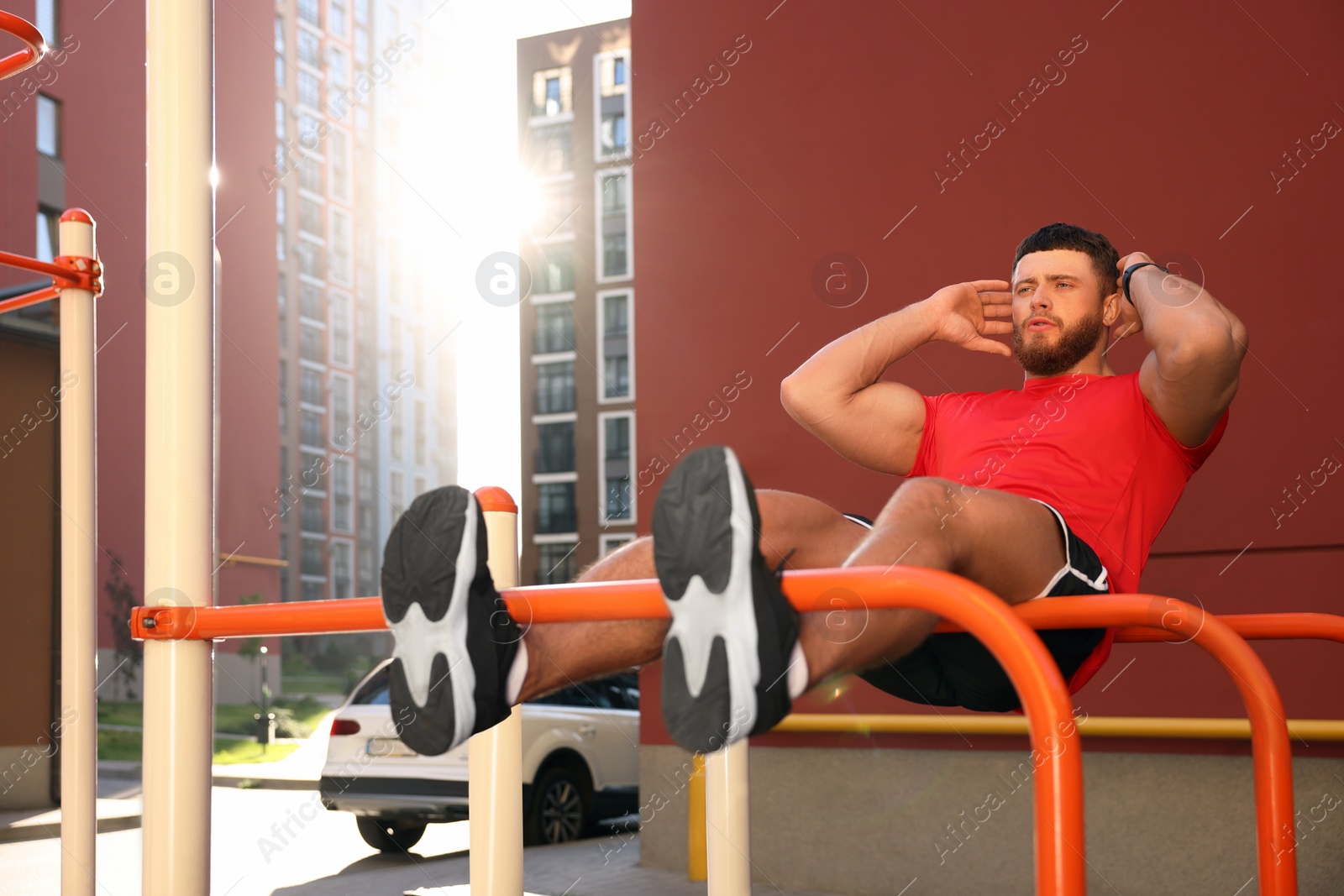 Photo of Man doing abs exercise on parallel bars at outdoor gym