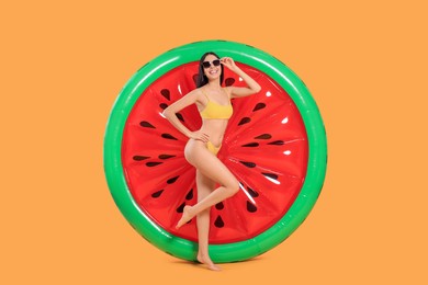 Photo of Happy young woman with beautiful suntan, sunglasses and inflatable mattress against orange background