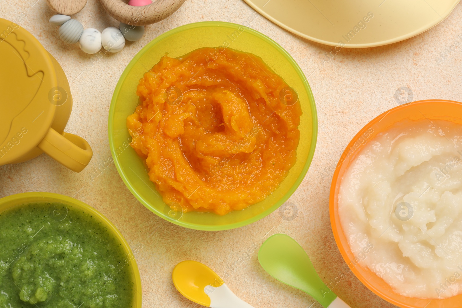 Photo of Baby food. Different tasty puree in bowls served on beige textured table, flat lay