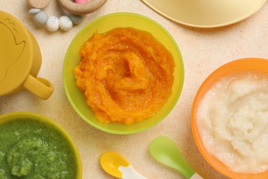 Baby food. Different tasty puree in bowls served on beige textured table, flat lay