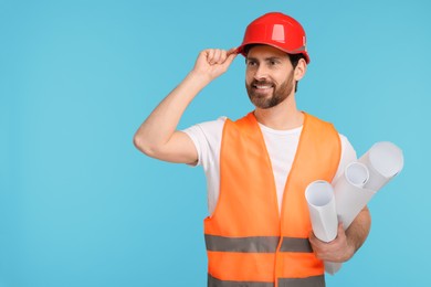 Architect in hard hat with drafts on light blue background, space for text