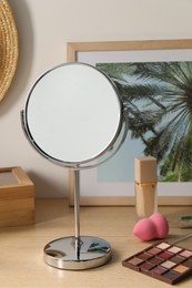 Mirror, picture and makeup products on wooden dressing table