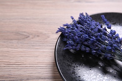 Photo of Bouquet of beautiful preserved lavender flowers and plate on wooden table, closeup. Space for text