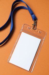 Photo of Blank badge with string on orange background, top view