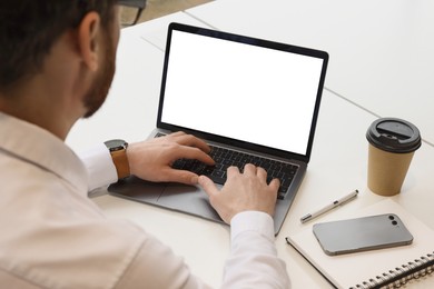 Man working on laptop at white desk in office, closeup