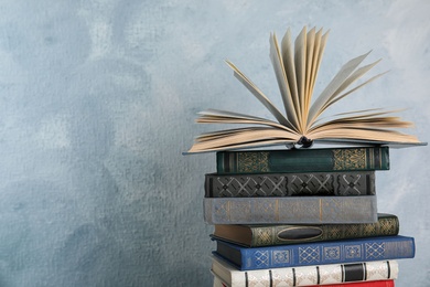 Stack of hardcover books on light blue background. Space for text