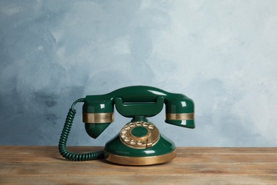 Photo of Vintage corded phone on wooden table against light blue background