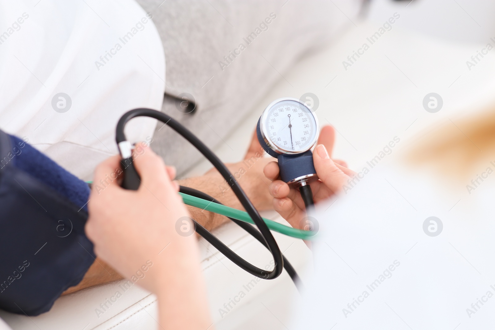 Photo of Doctor checking blood pressure of man in clinic, closeup